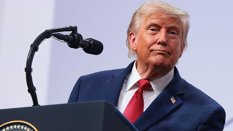 President Donald Trump speaking on stage during a press conference at the G7 Leaders' Summit