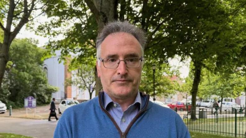 Patrick Lynch is pictured in parade gardens. He is wearing a blue fleece and a blue shirt.