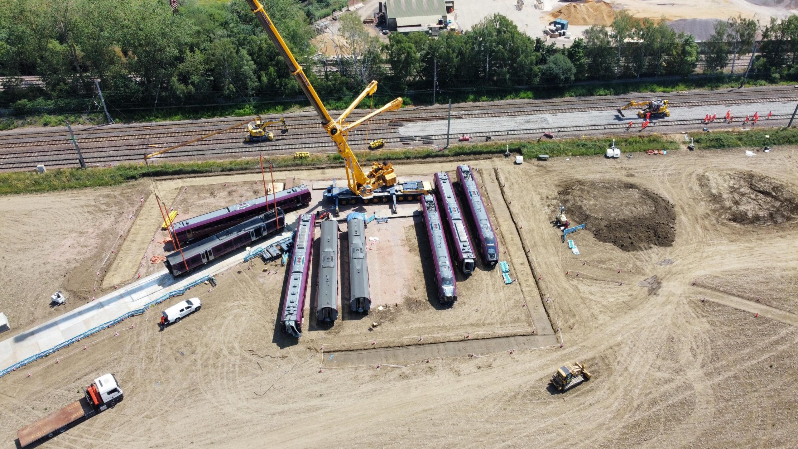 Train carriages on a piece of land next to a railway, with a couple being moved on to a make shift road