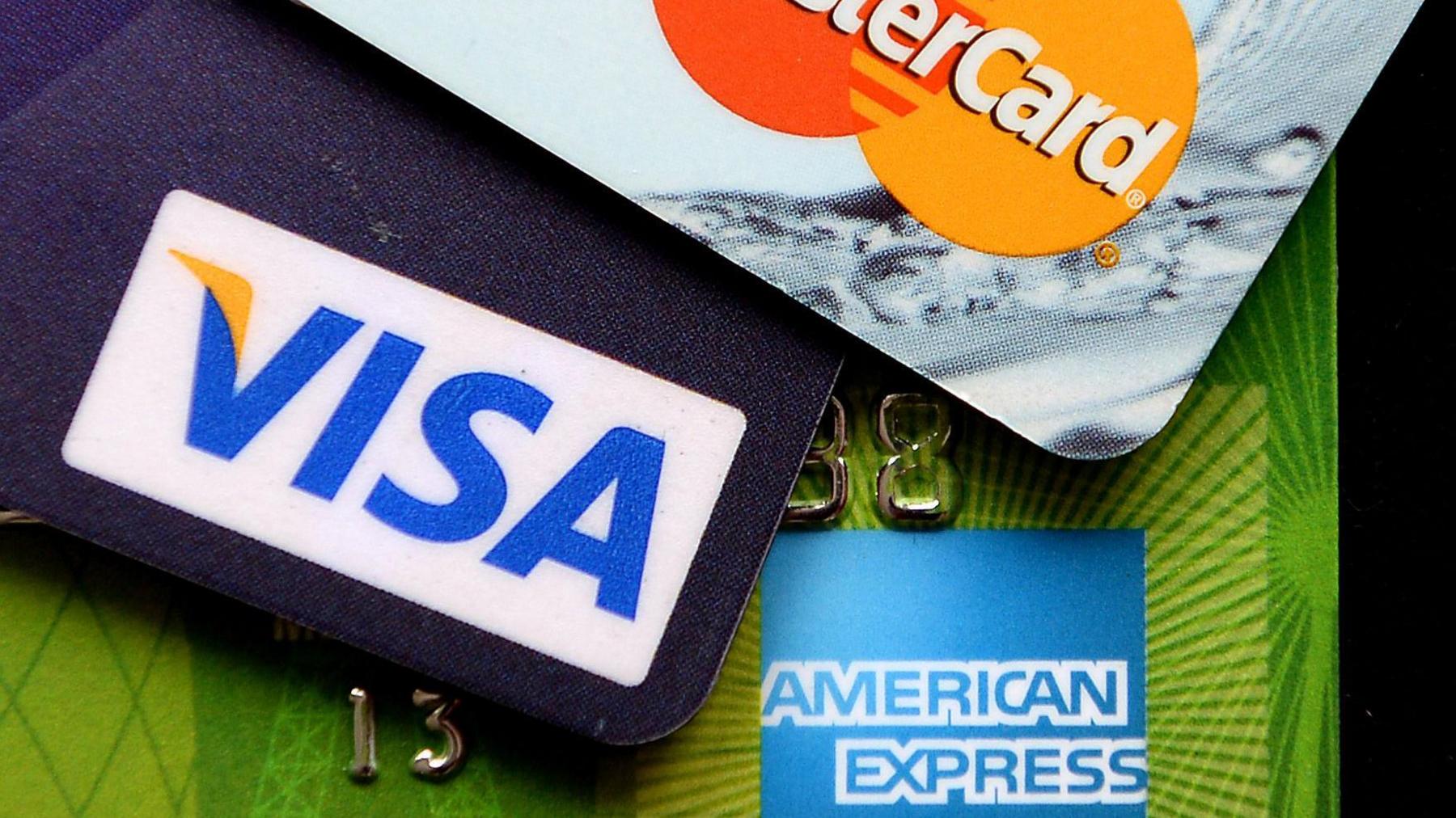 A Visa, a MasterCard and an American Express credit card next to each other.