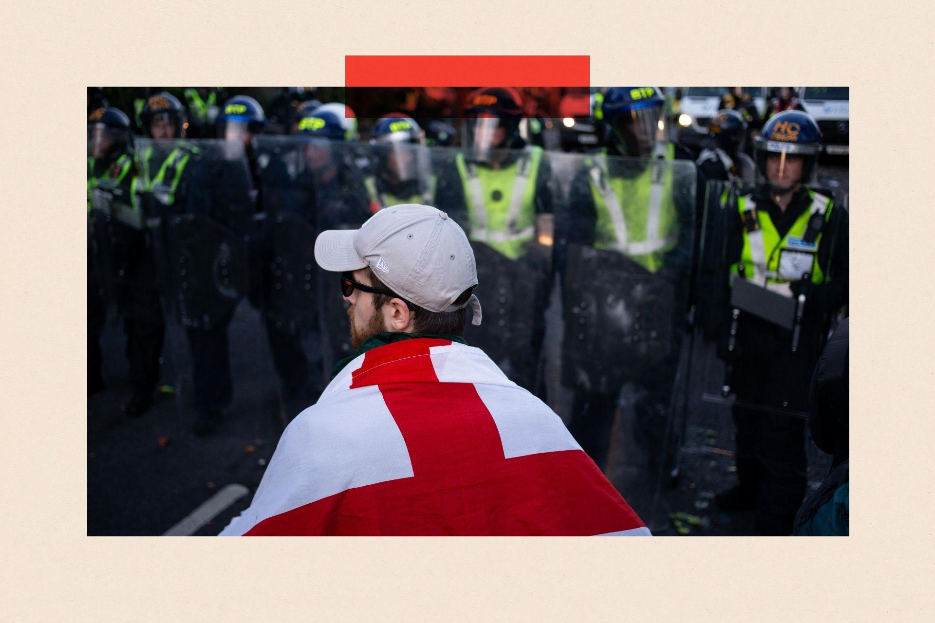 A man drapped in an England flag stands in front of police lines as clashes erupt in Southampton