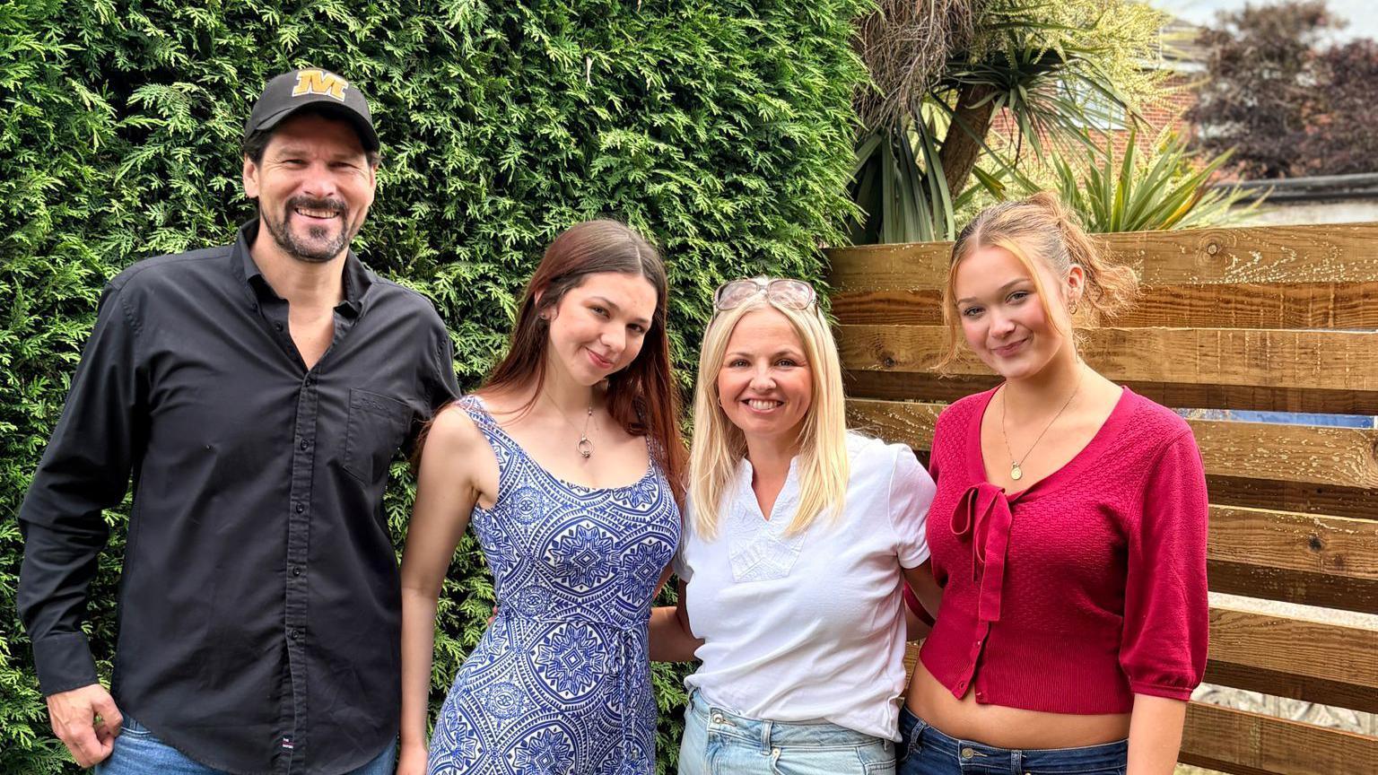 Lee on the left wearing a black shirt and baseball cap. His daughter is net to him, then Sarah and then their other daughter.