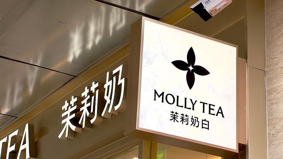 A view of Molly Tea's four-petal flower logo on a sign hanging on the sign of one of the brand's shops.