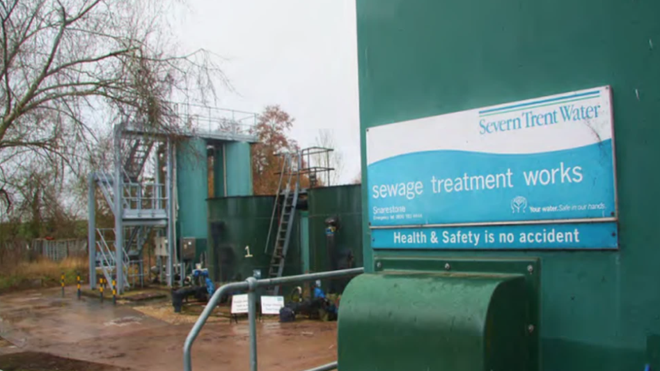 A waste water plant. A large blue and white sign advertising Severn Trent's sewage treatment works hangs on the side of the building.