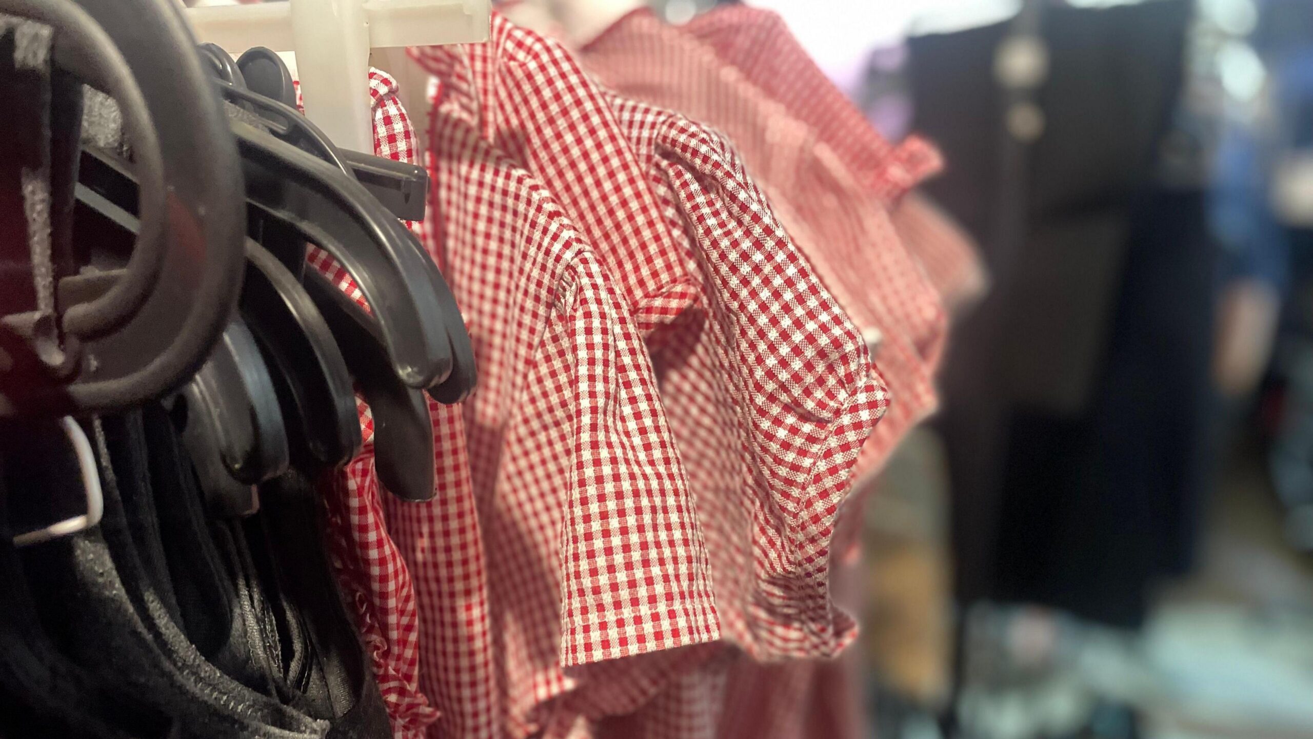Racks of uniforms - several red and white checked dresses.