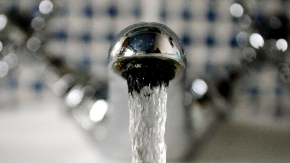 A bathroom tap with flowing water