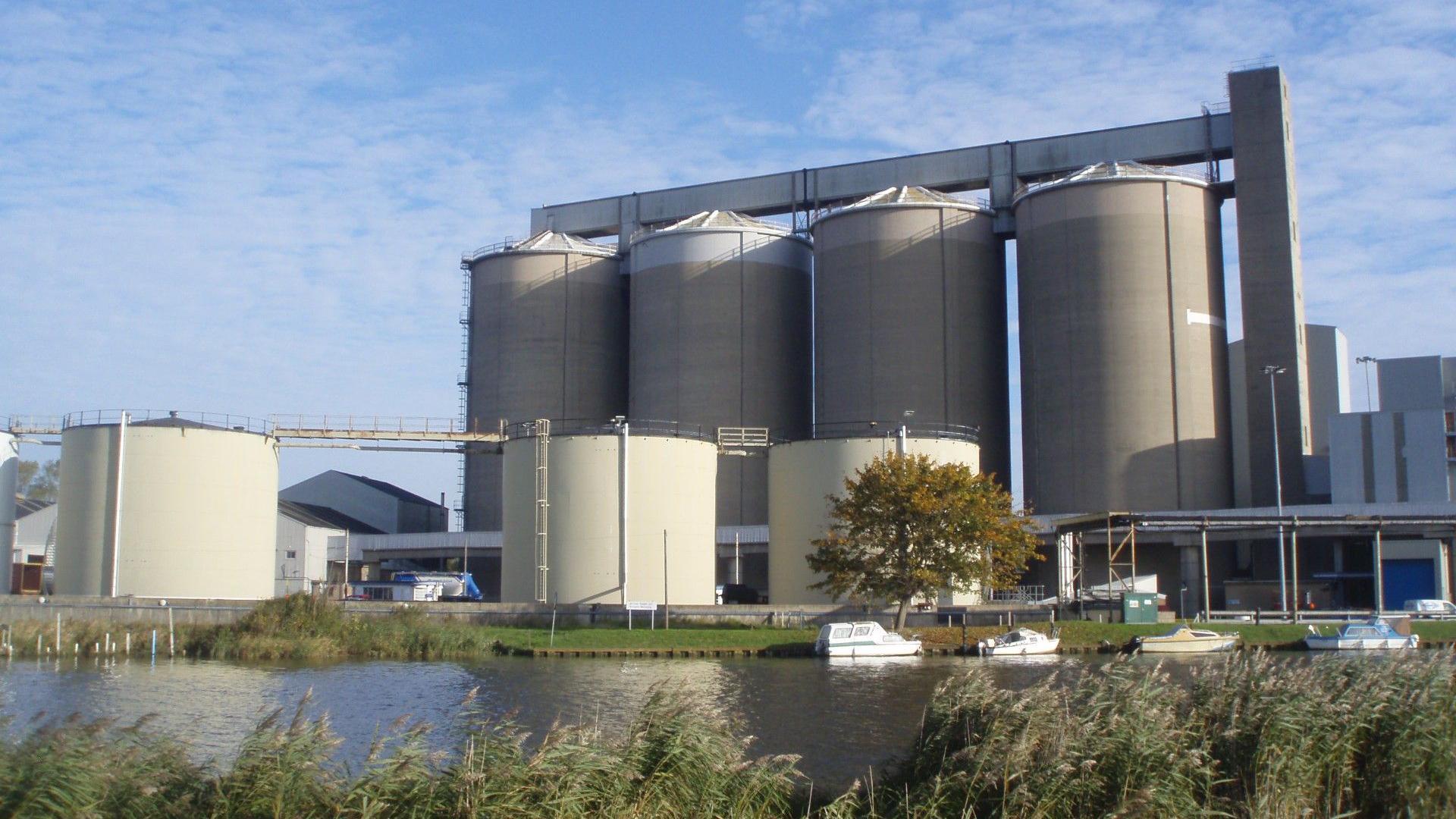 Sugar storage silos at Cantley sugar factory with a river in the foreground on a clear day