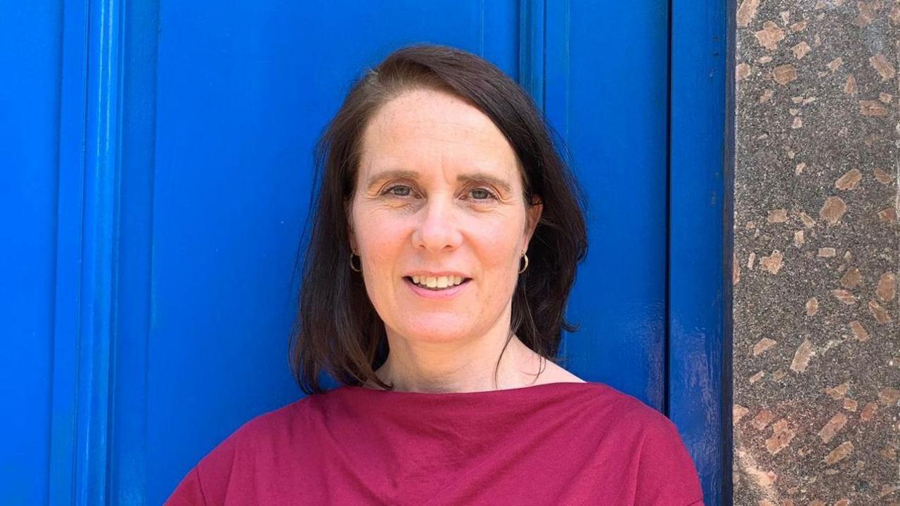 Siobhan has shoulder length dark hair and is wearing a pink top.