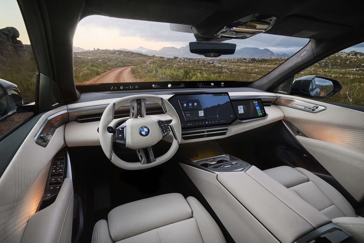 Modern BMW X5 interior with a panoramic view, beige leather seats, and large digital displays