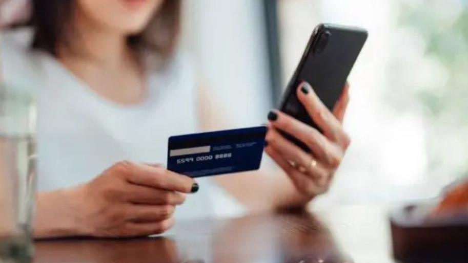 Stock image of female hands holding a credit card and looking at a phone