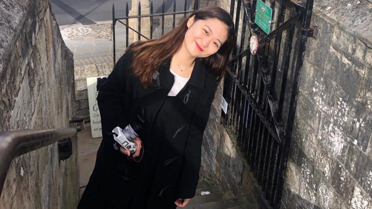 Jacqueline Choi, 28, poses for a picture, smiling as she leans towards her left.