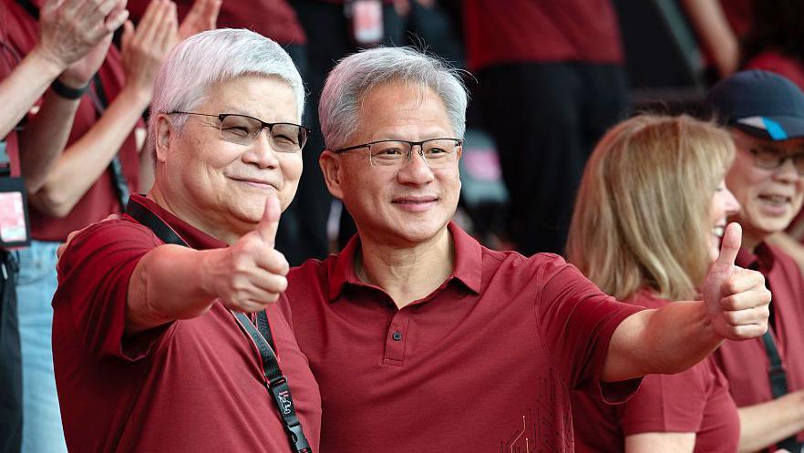 Jensen Huang, chief executive officer of Nvidia (right), poses for photographs with TSMC boss CC Wei smiling with their thumbs up. Both men are dressed in red polo t-shirts
