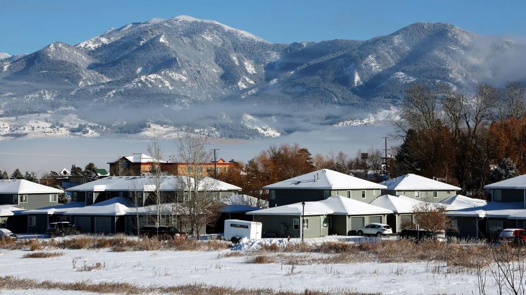 A new housing development sits at the base of a snowy mountain range